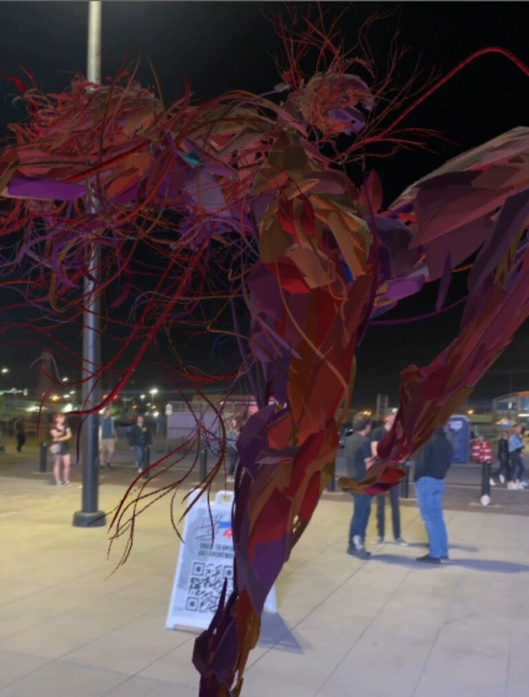 A towering AR sculpture of red, tangled strands appears over the plaza at night beside a QR code sign and visitors