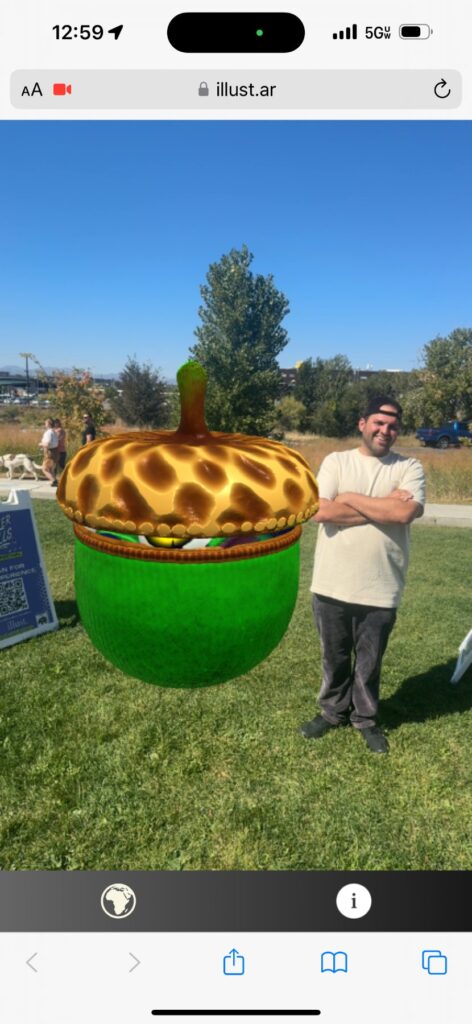 Phone screenshot of a green AR acorn character next to a visitor in a park, running in the phone's web browser